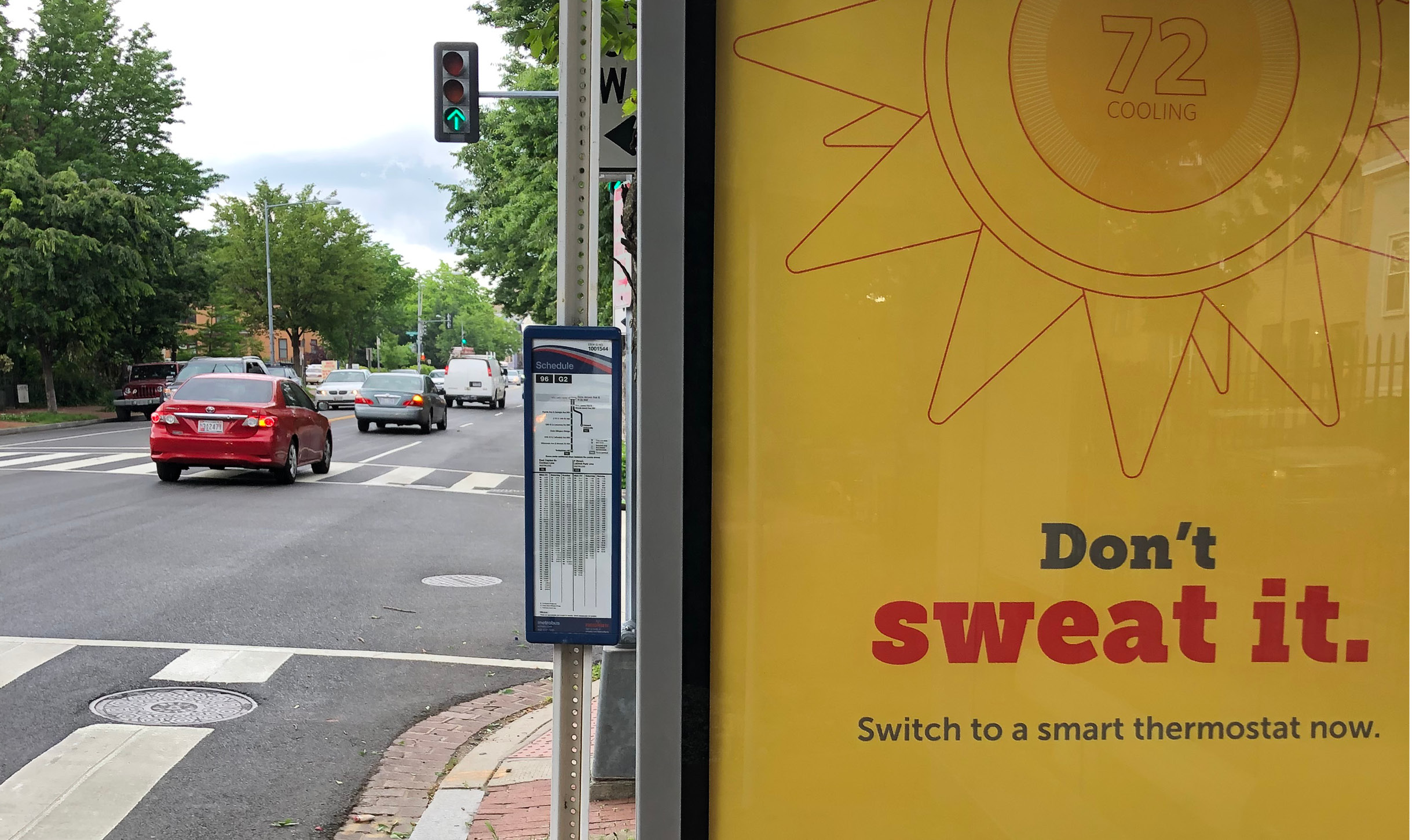 Close-up of a bus shelter with a DCSEU ad in it readng Don't Sweat It — Switch to a smart thermostate now